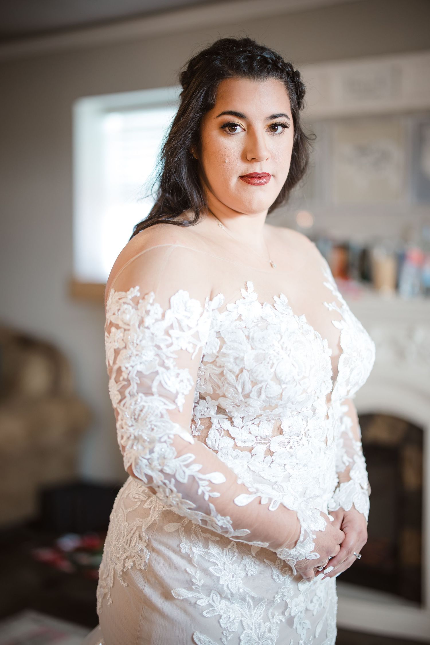 Close-up details of delicate white lace appliques on sheer wedding gown with long sleeves.