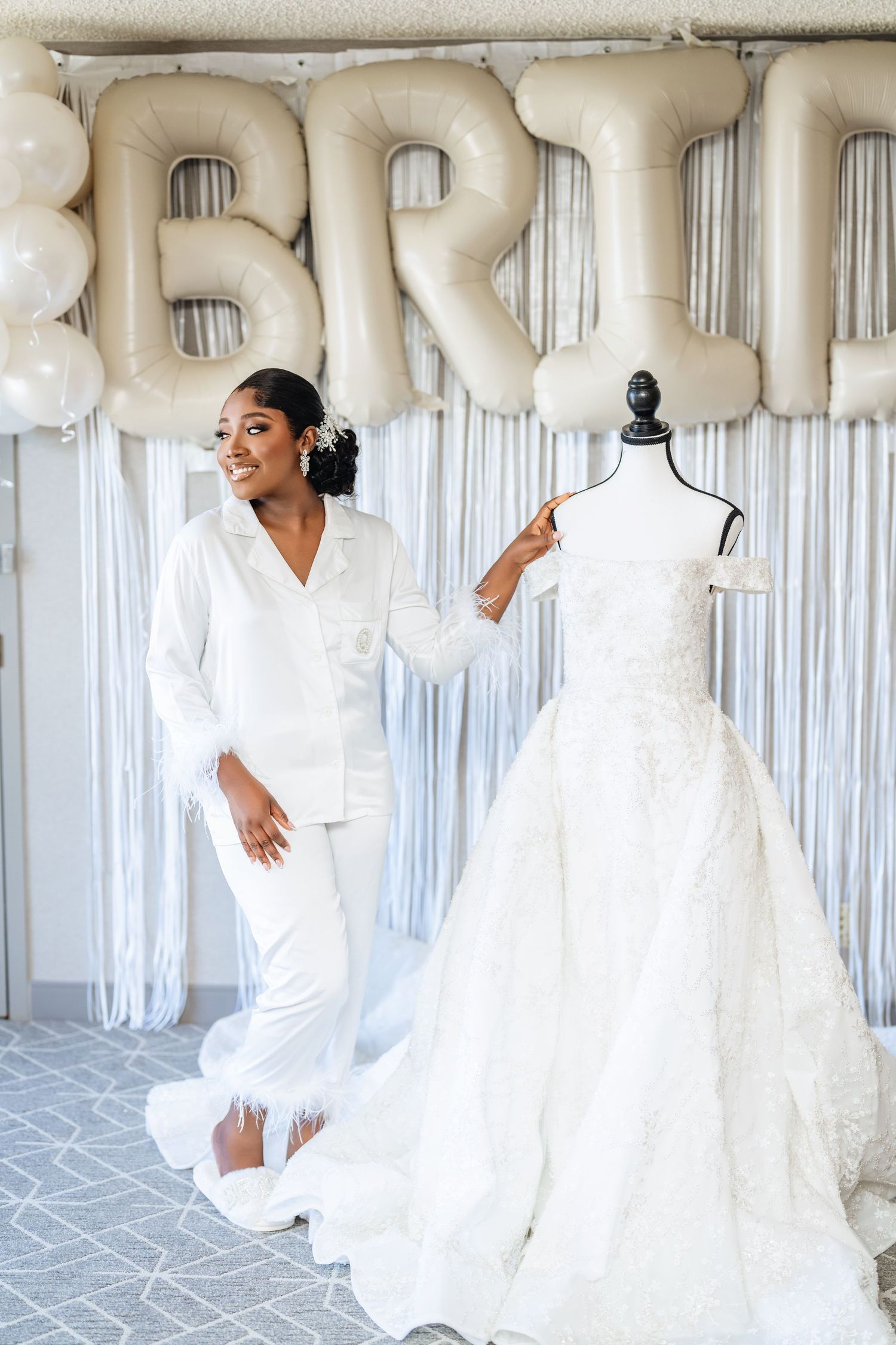 Wedding preparations with a white bridal gown displayed on mannequin next to balloon letters spelling BRIDE.