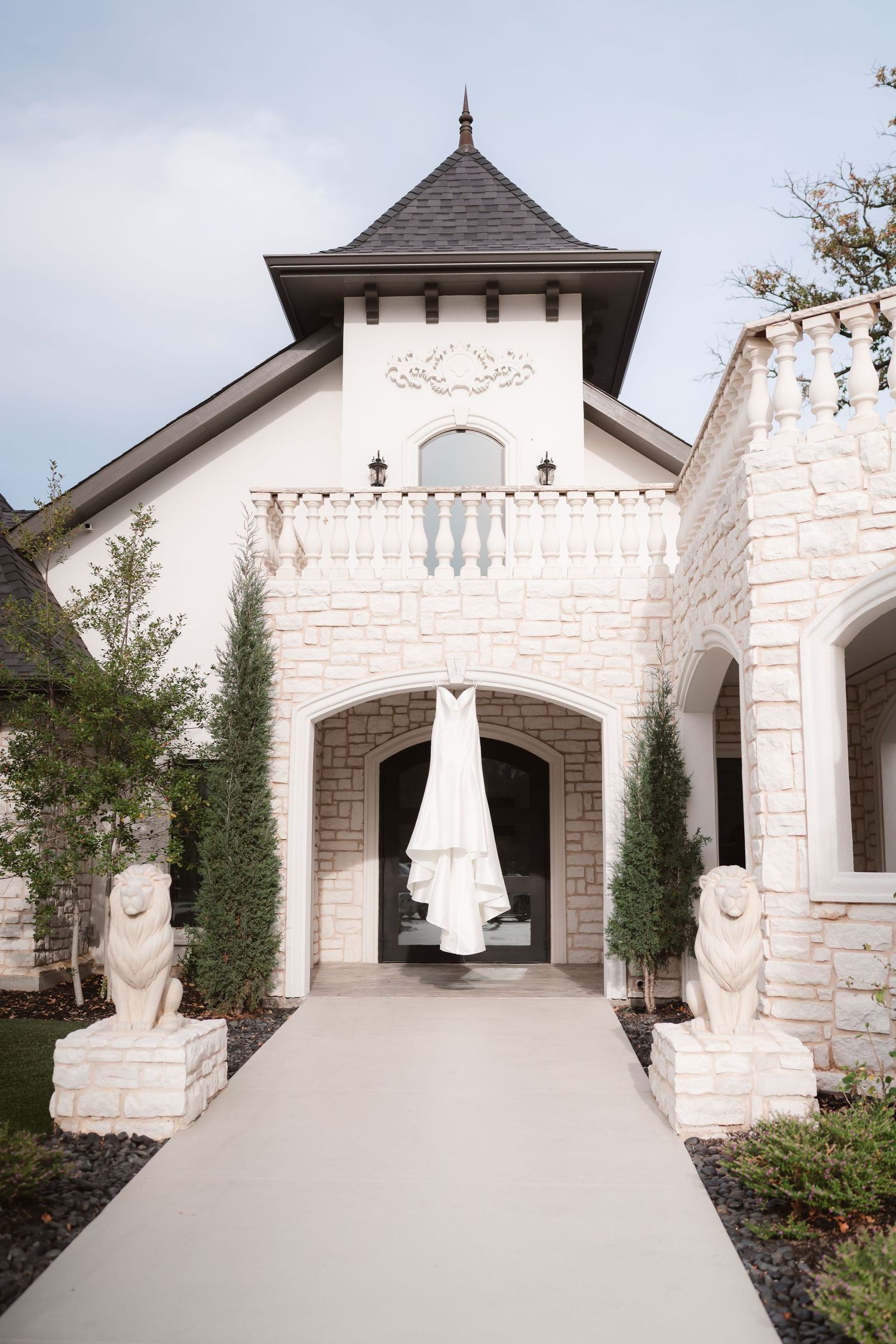 White stone chapel with elegant architecture and wedding dress displayed outside.