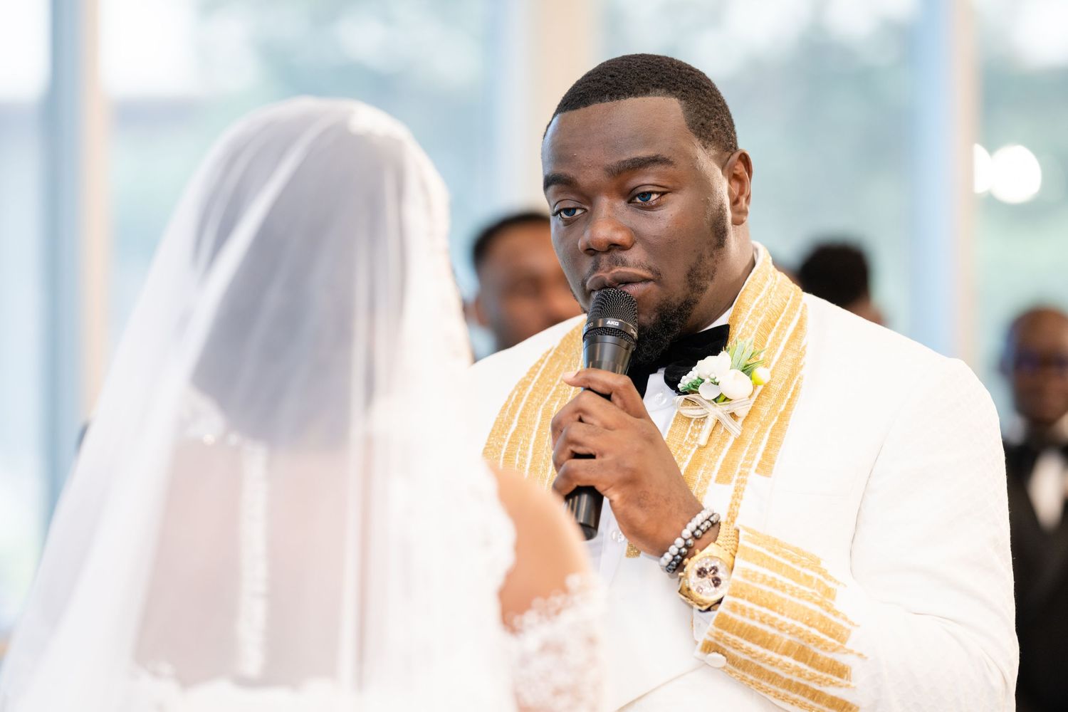 Wedding ceremony scene with white drapes and golden accents in the background.