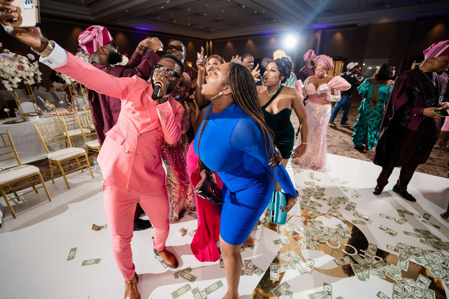 Joyful wedding reception scene with guests dancing and celebrating on a confetti-covered dance floor.
