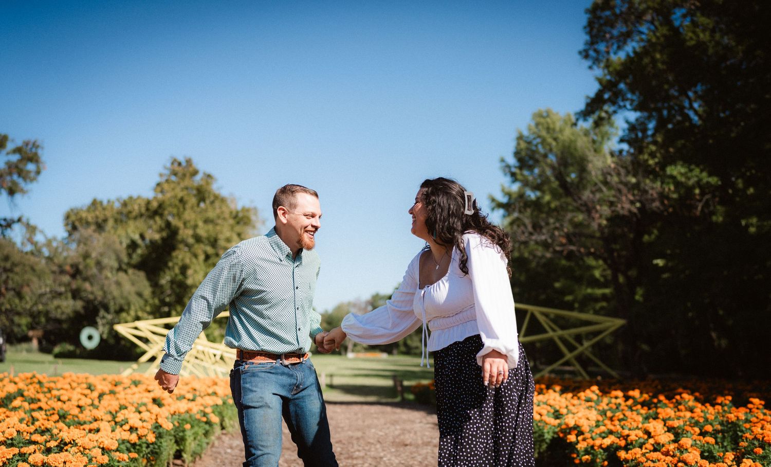 Couple walks through vibrant orange pumpkin patch on sunny autumn day at local farm.