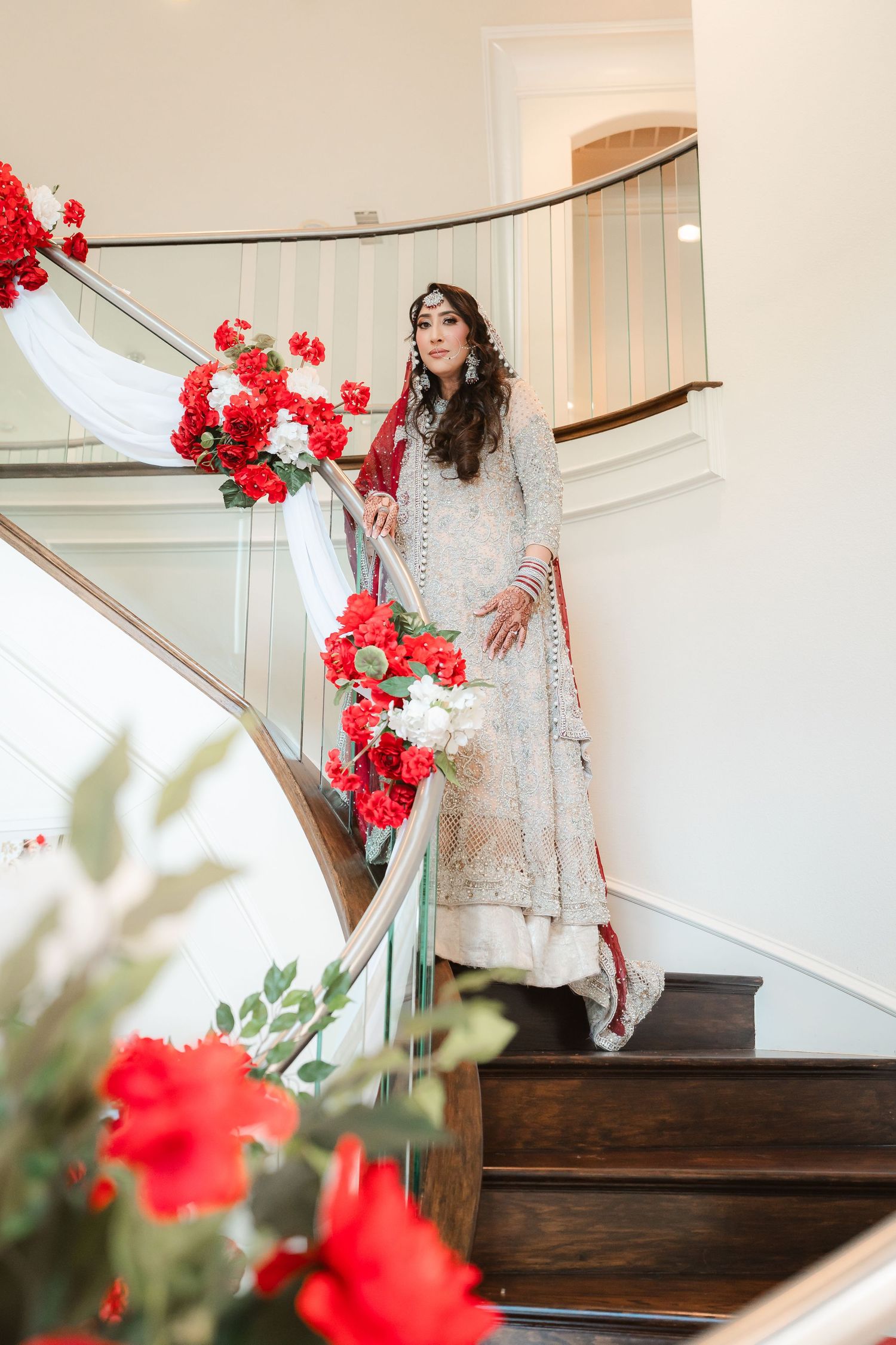 Elegant staircase decorated with red and white flowers in a modern interior setting.