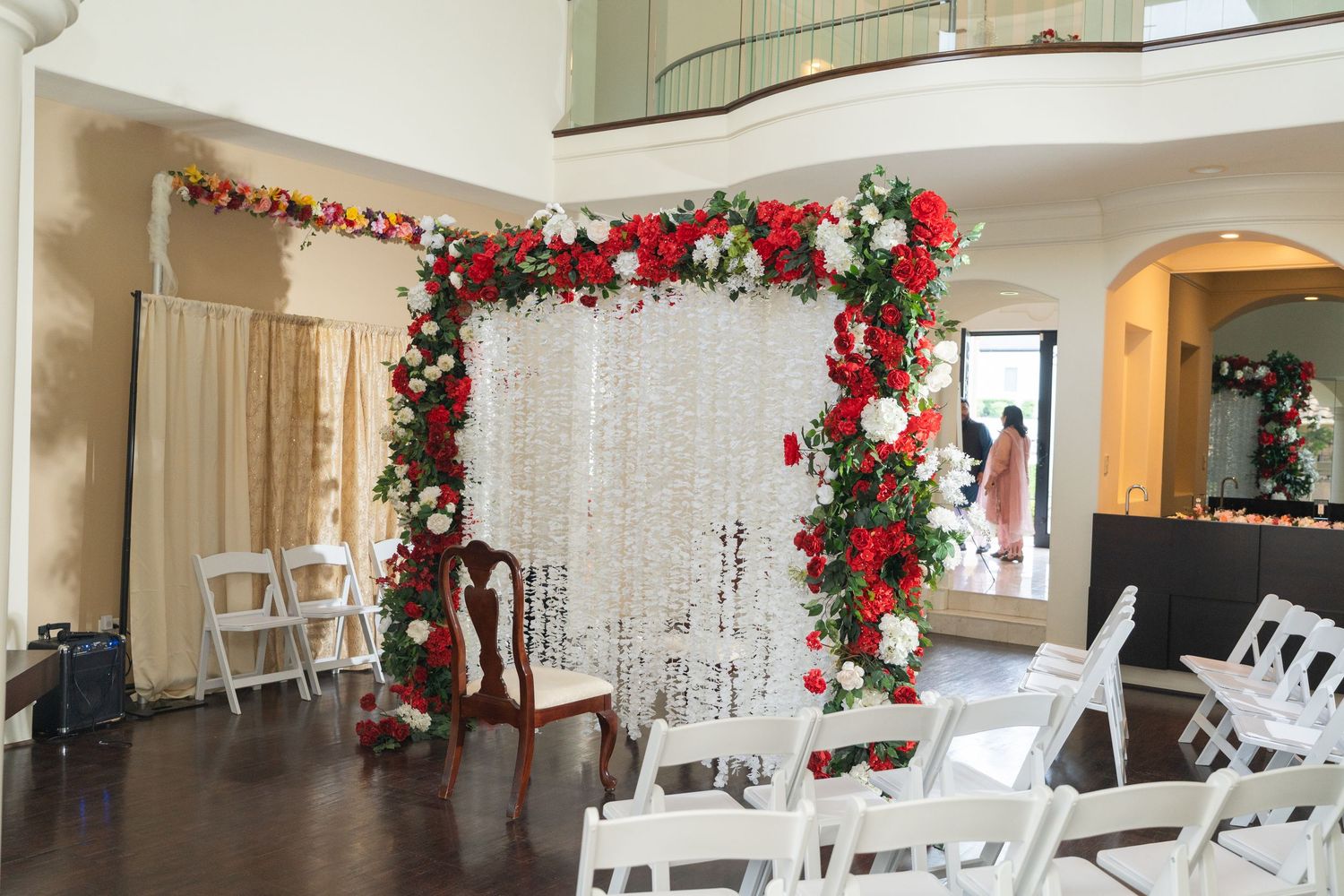 Elegant wedding venue decorated with red and white floral arrangements and crystal chandeliers.
