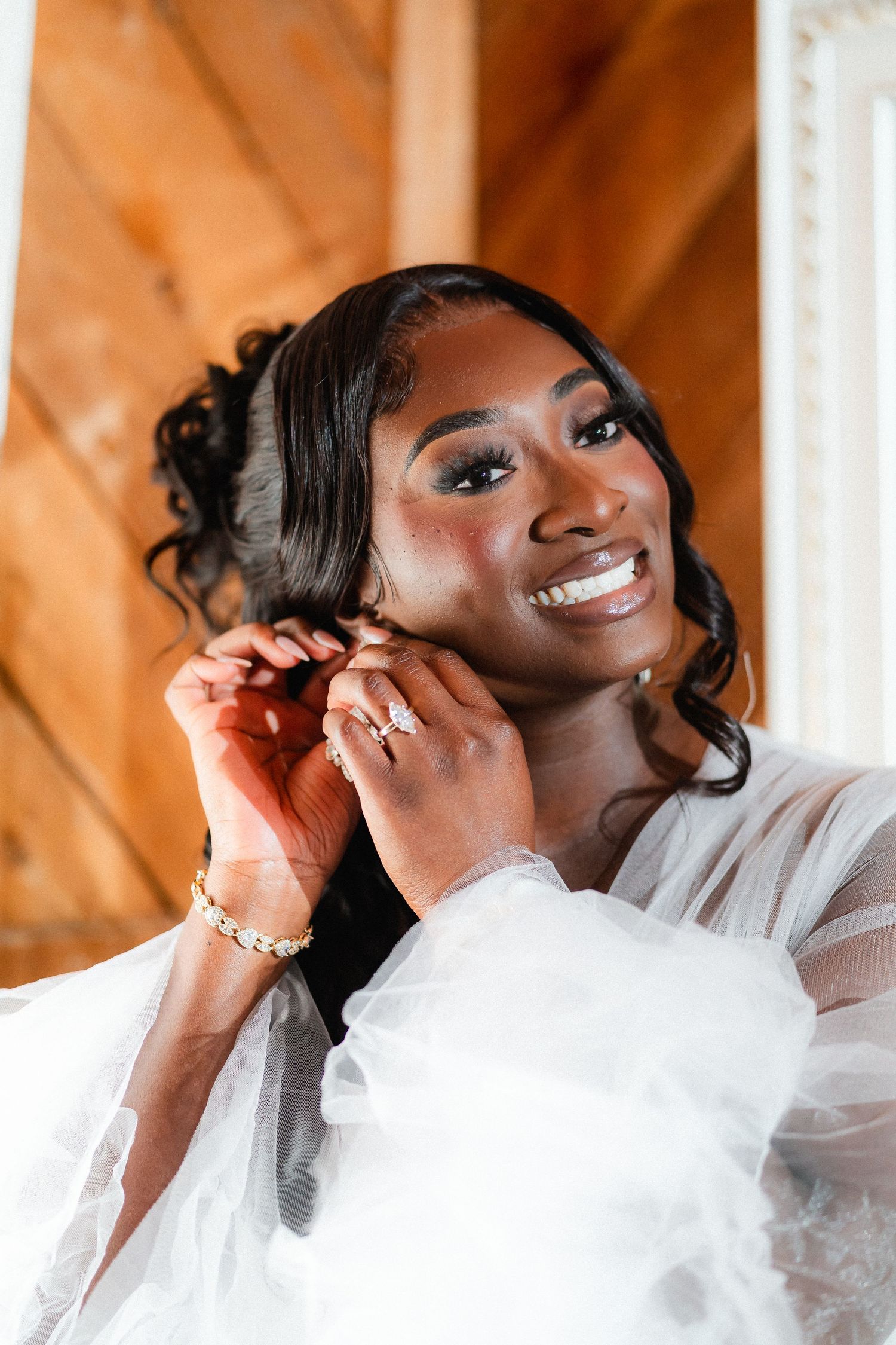 Smiling bride in white tulle gown poses playfully in three sequential portrait shots with warm wooden backdrop.