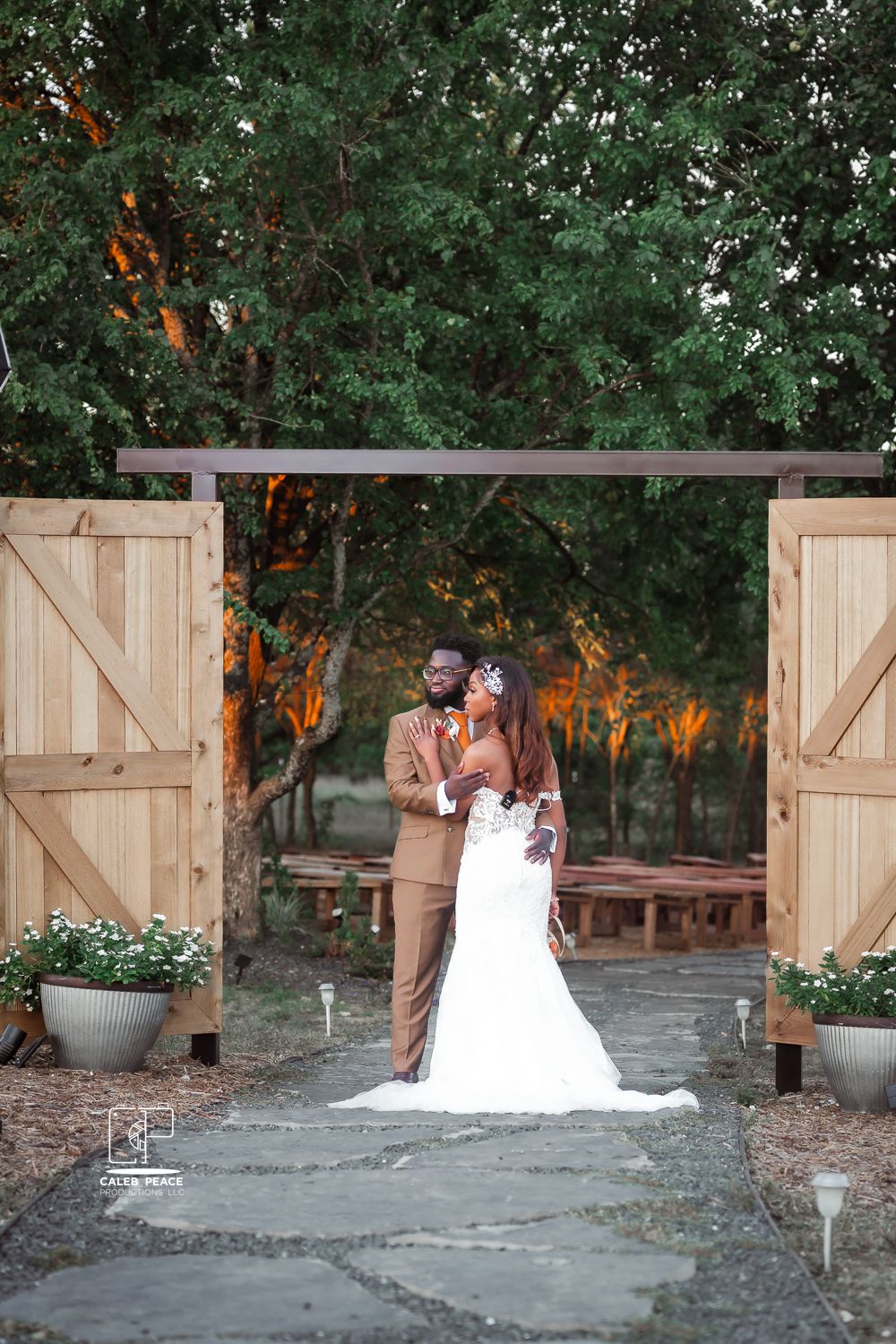 Elegant wedding portraits taken against rustic wooden barn doors at sunset.