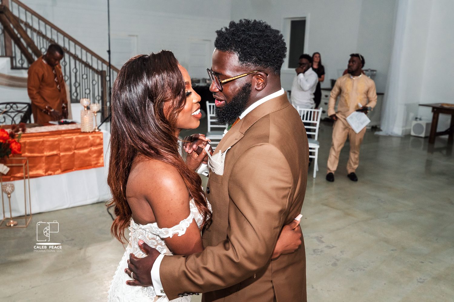 Wedding couple and guests share intimate moments in an indoor venue with white walls.