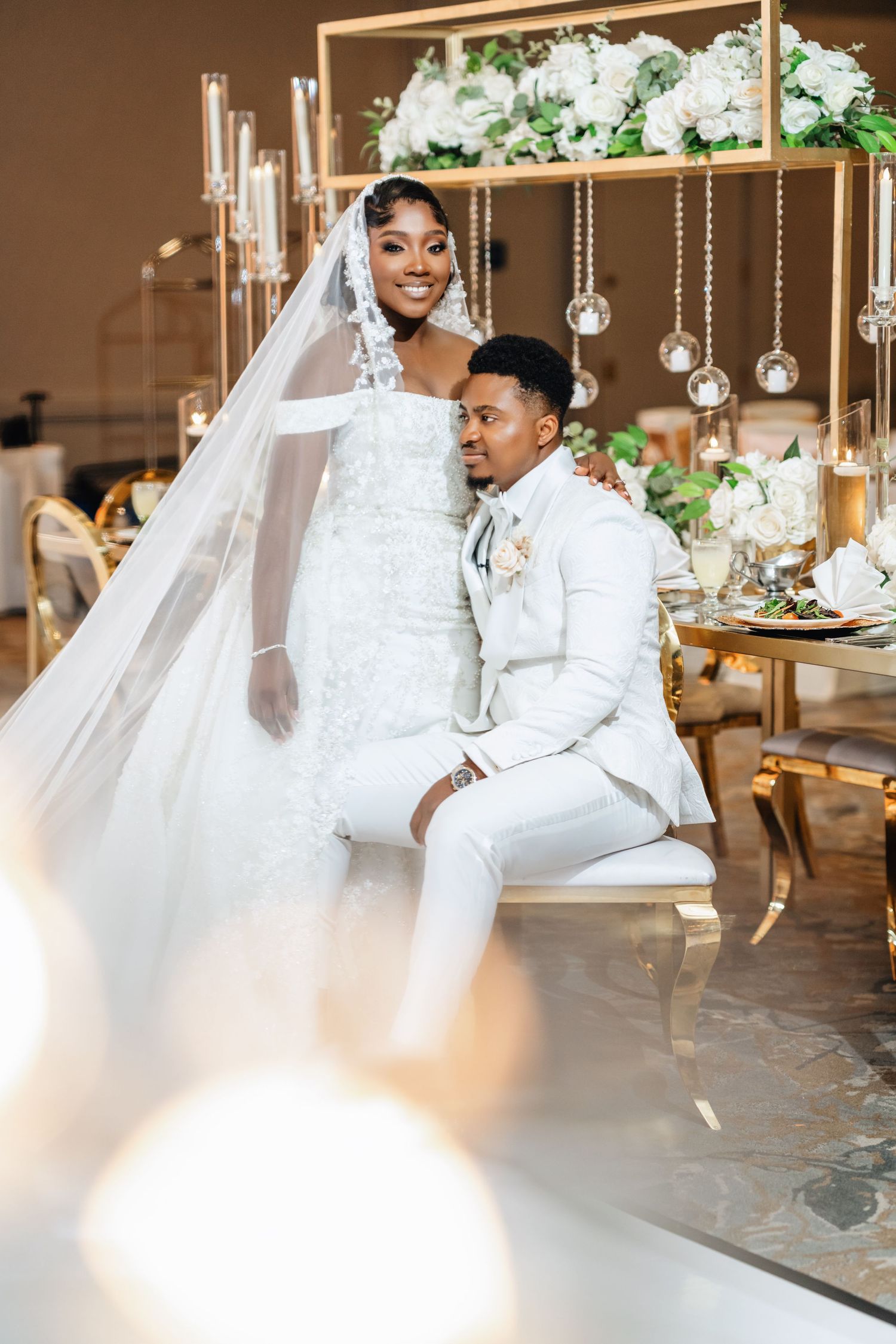 Elegant wedding scene with floral decor and hanging crystal ornaments in a luxurious venue setting.