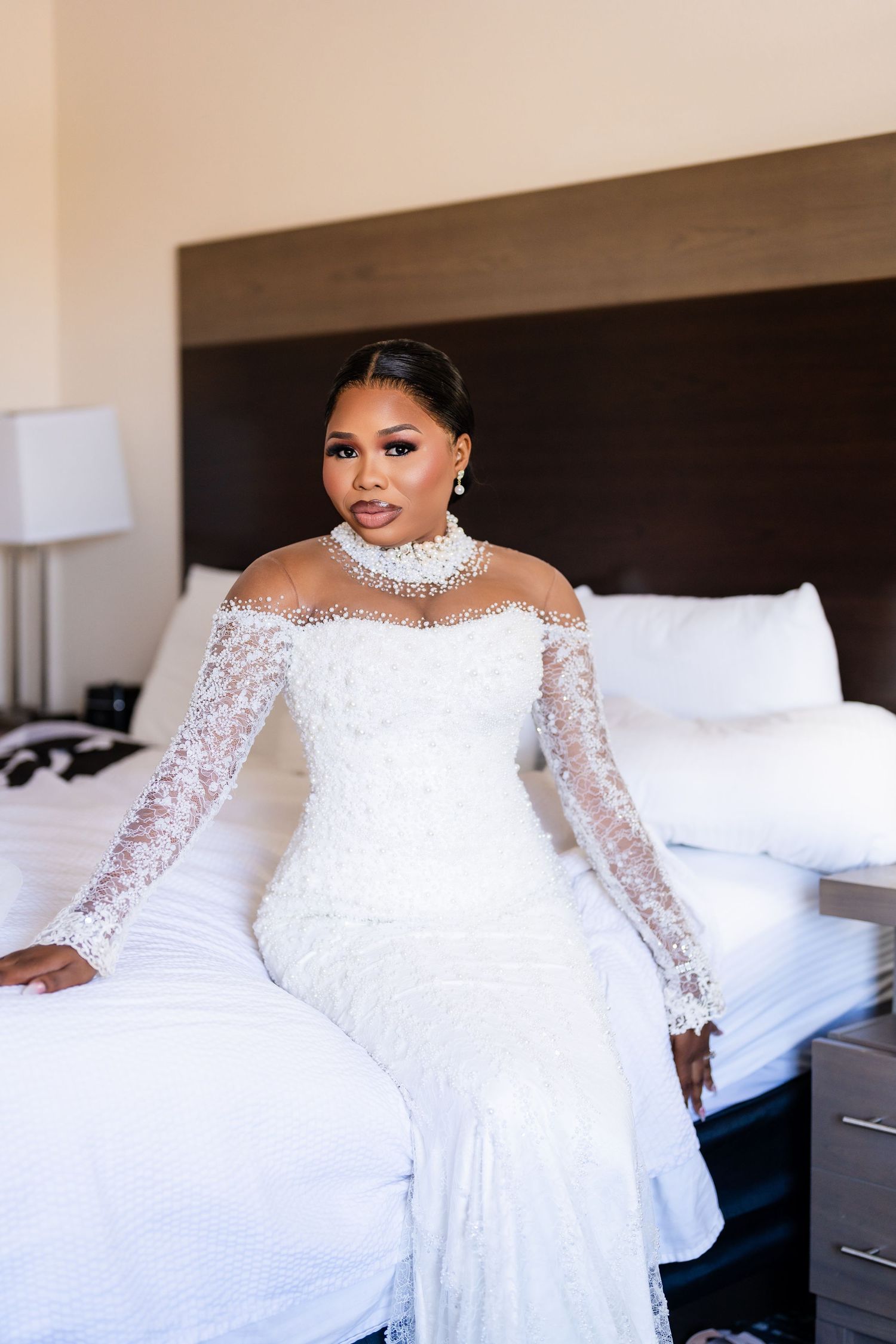 Elegant white lace wedding gown with long sleeves and high neckline displayed in a bridal suite.