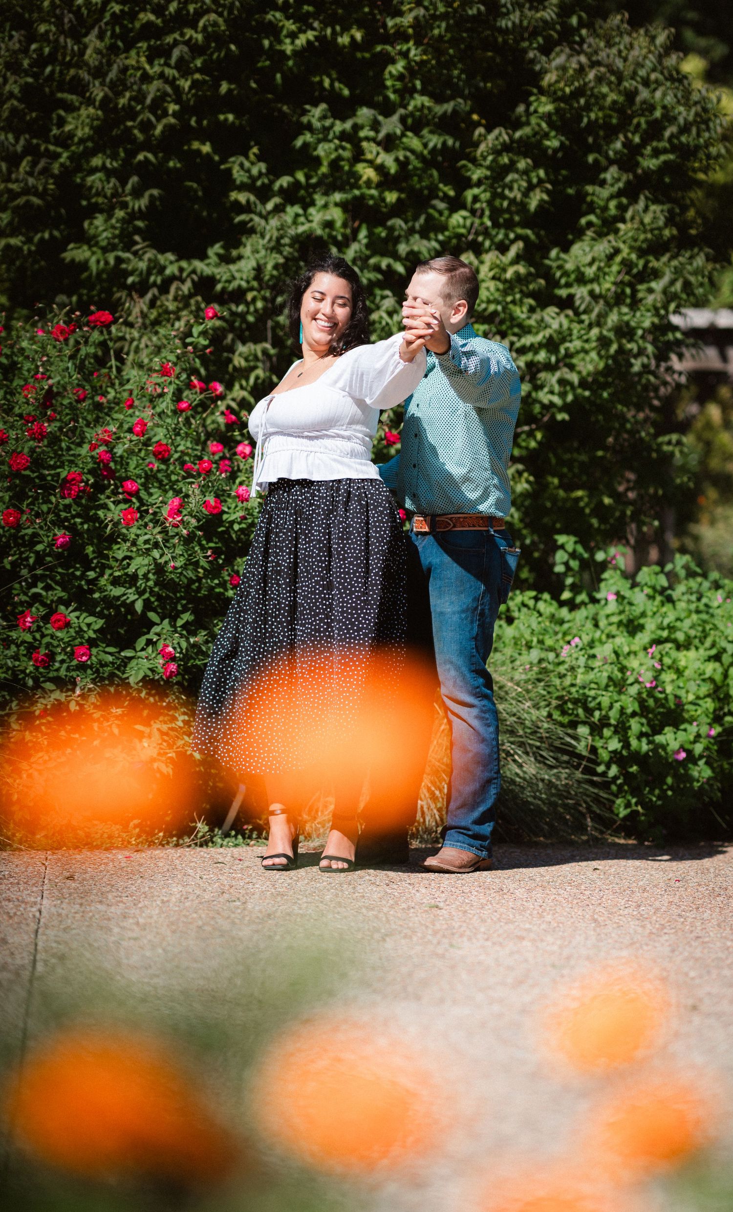 A romantic moment between a couple dancing in a garden with vibrant orange flowers in the foreground.