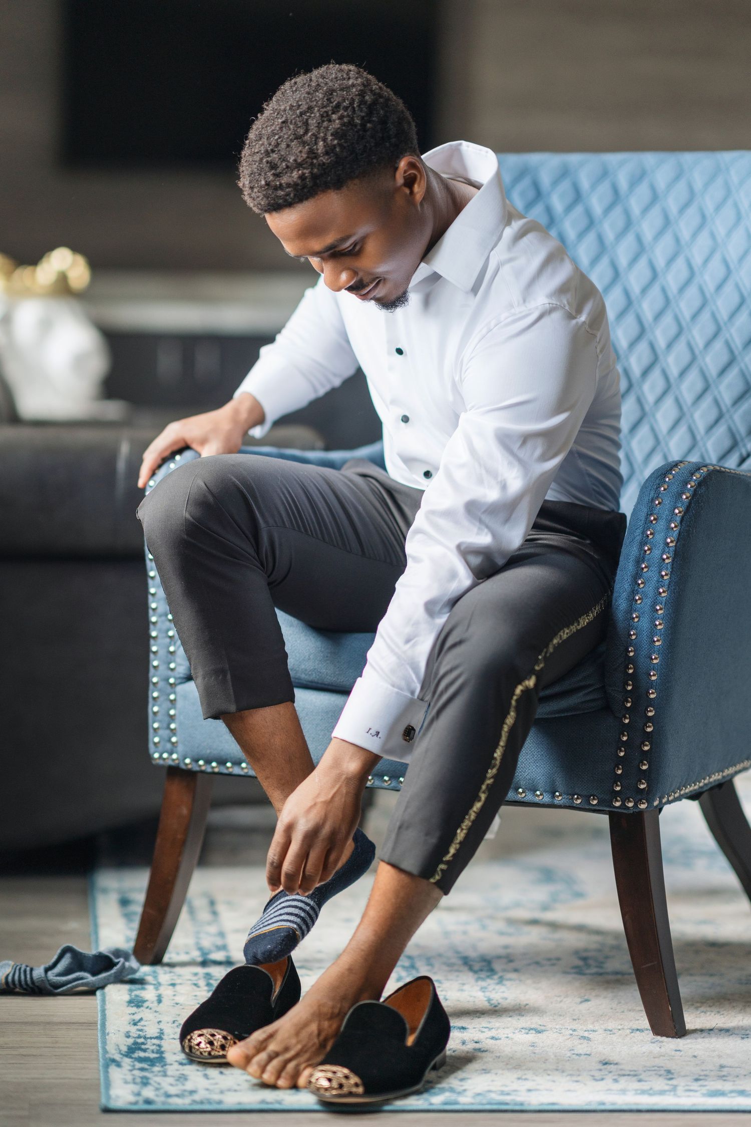 Close-up shots of someone putting on formal footwear while seated in a blue chair.
