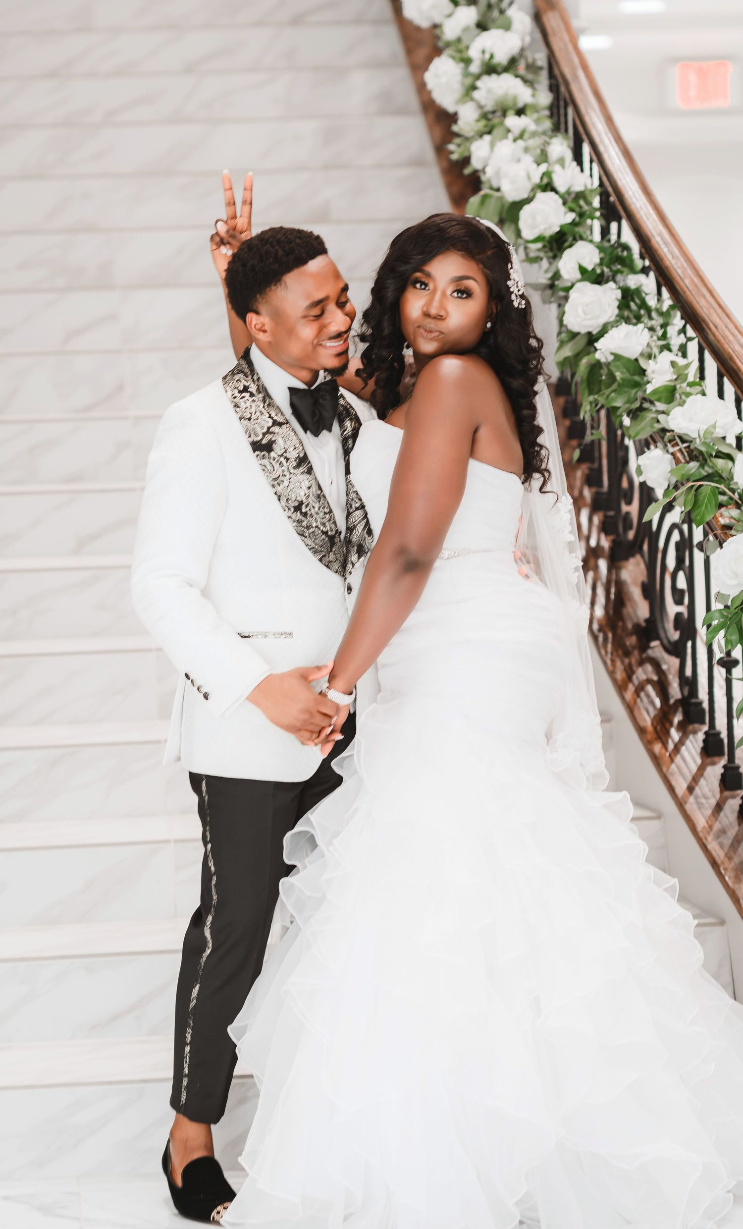 Wedding couple shares romantic moment on grand staircase decorated with white florals.