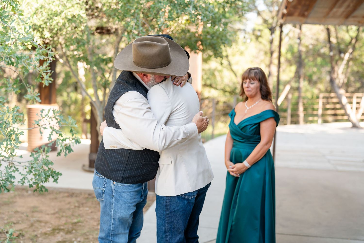 Wedding party members interacting outdoors near trees during a celebration.