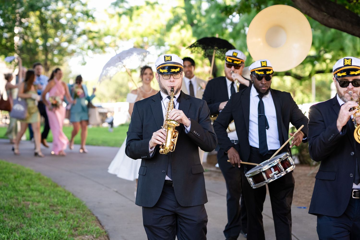 A brass band in naval uniforms performs during an outdoor wedding celebration.