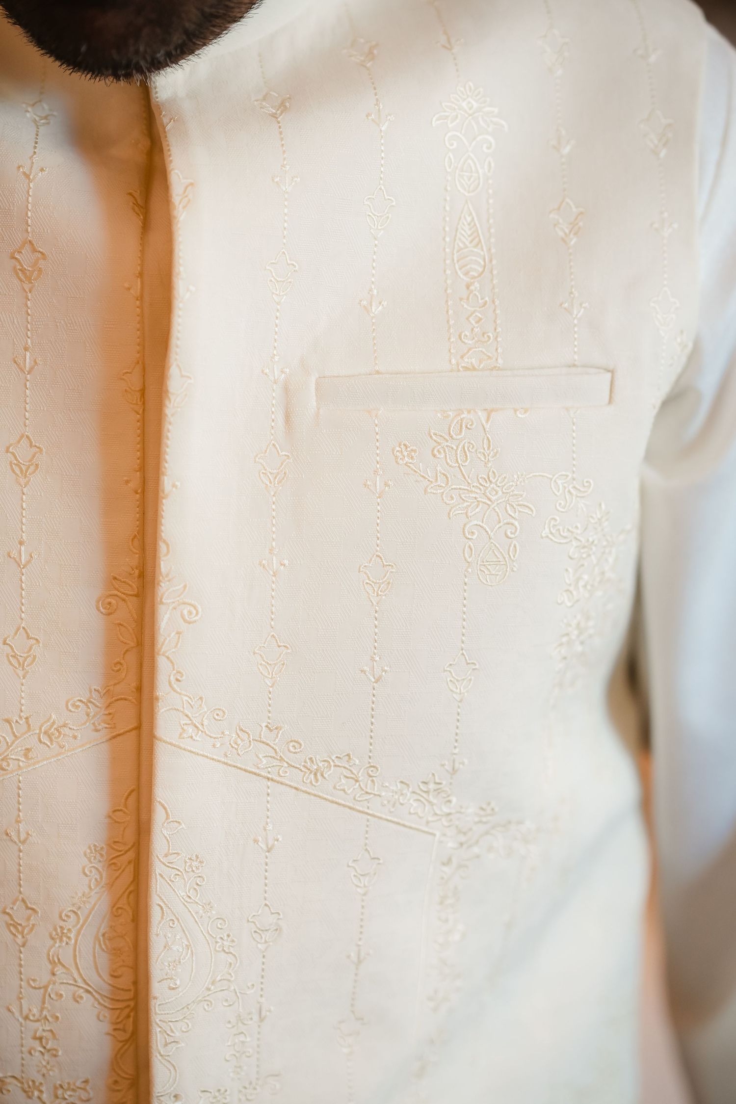Detailed view of delicate embroidery pattern on white formal wedding attire.