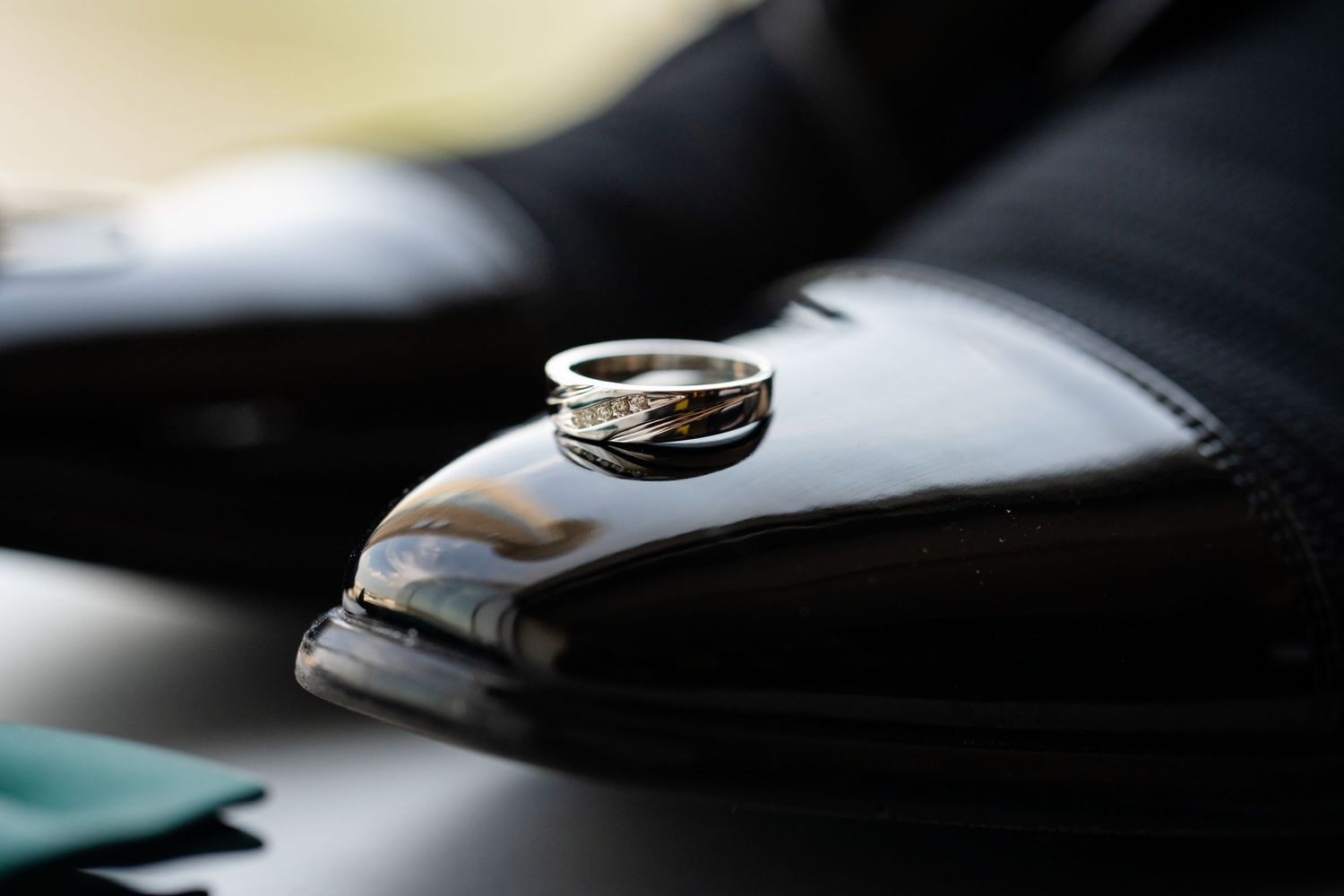 Wedding rings displayed artistically with a green bow tie and formal shoes.