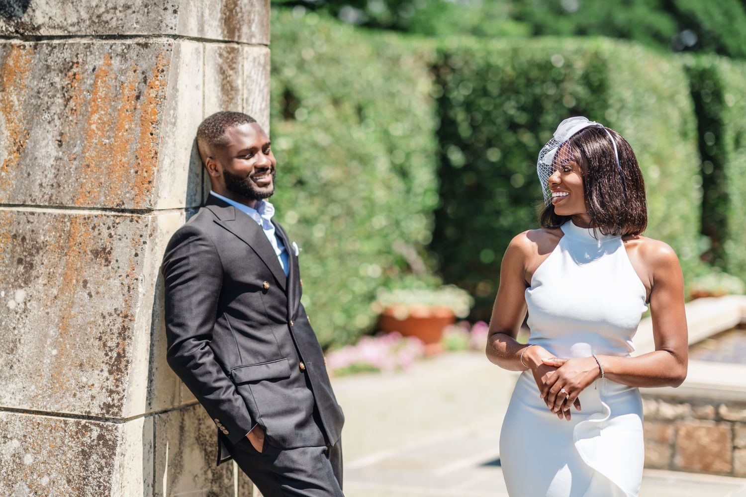 Romantic wedding photo sequence captured against stone pillars in a garden landscape.