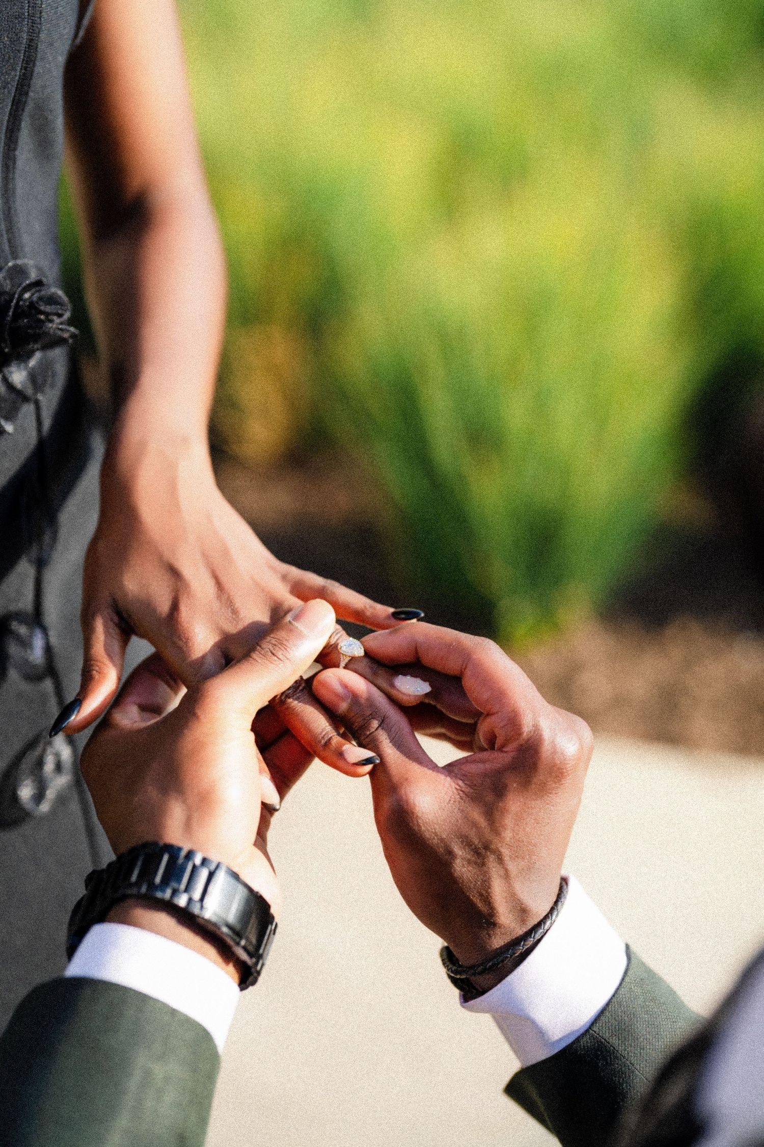 Close-up shot of hands during a ring exchange ceremony outdoors.