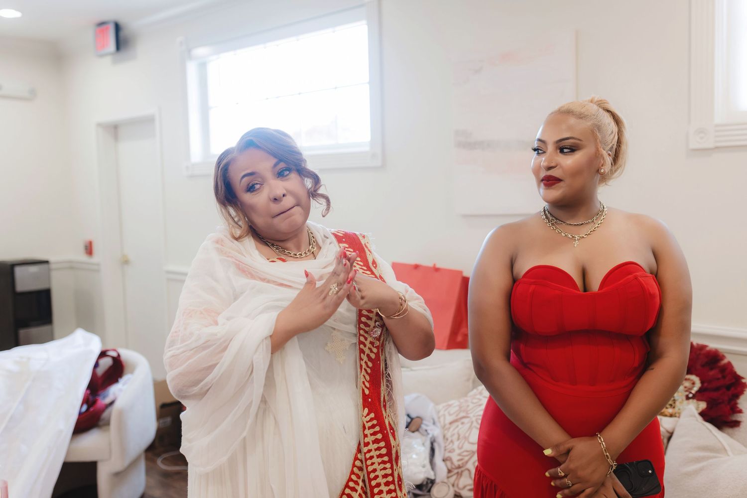 Wedding party members in red dresses and formal attire pose together.