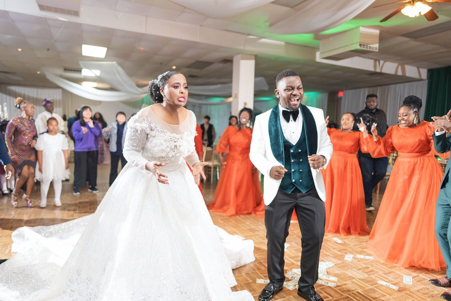 Wedding celebration with bridesmaids in orange dresses dancing at reception.
