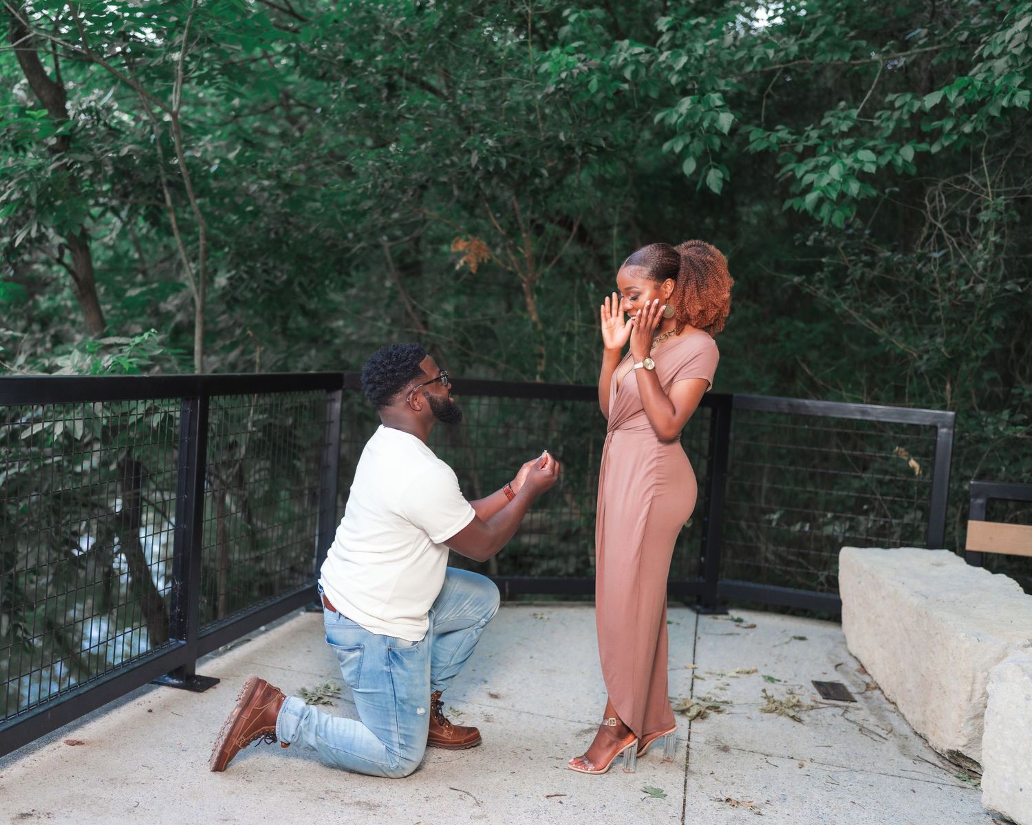 A couple shares a romantic moment on outdoor stone steps surrounded by greenery.