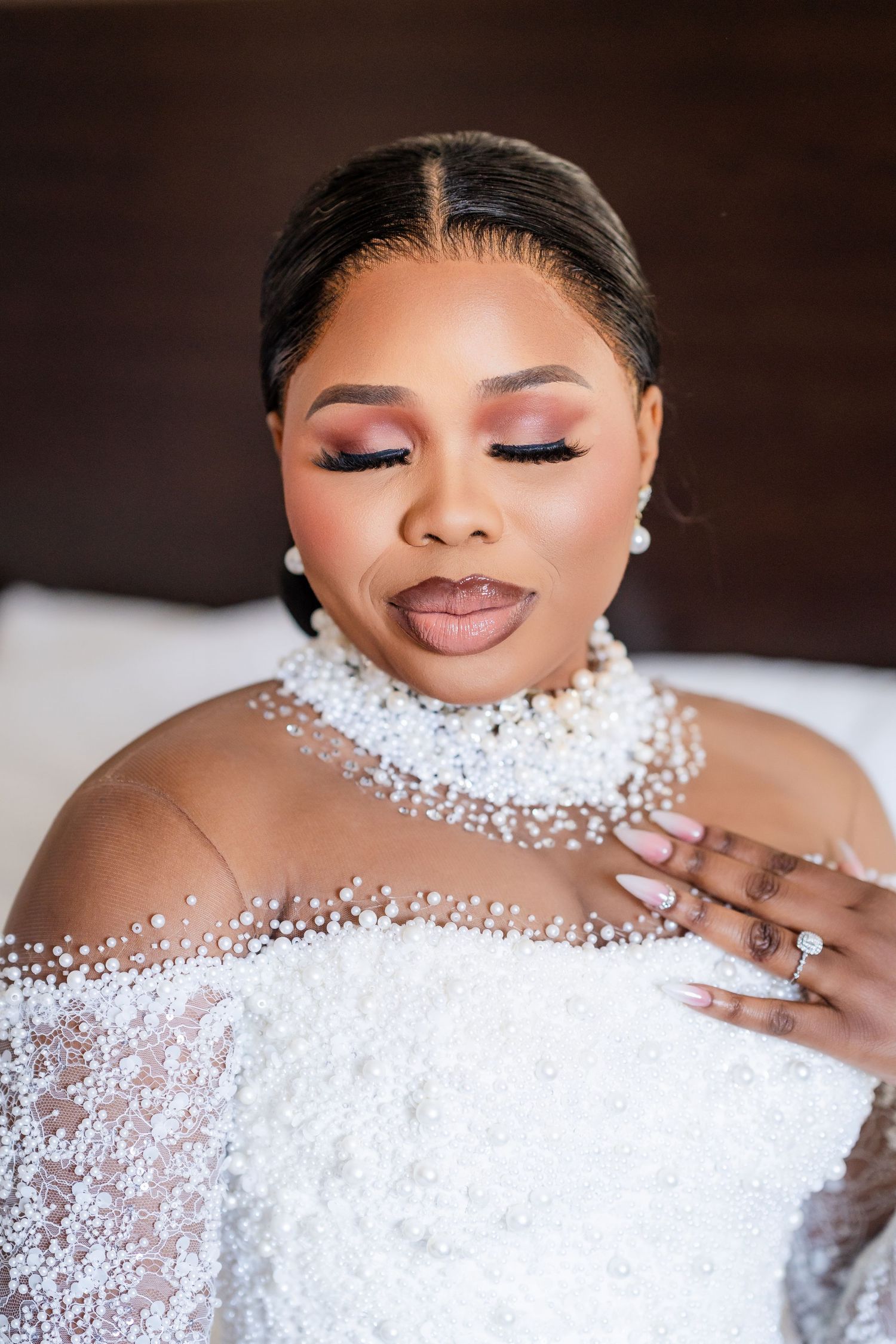 Close-up portrait showing elegant pearl neckline details and glamorous makeup.