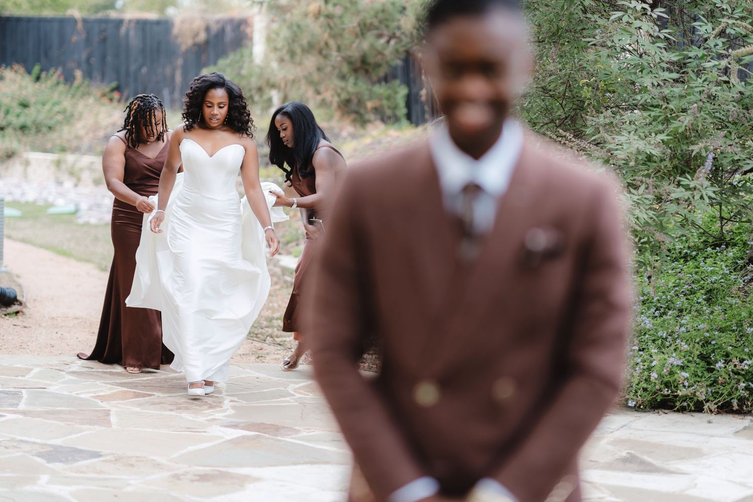 Romantic outdoor wedding photoshoot with couple in white dress and brown suit among greenery.