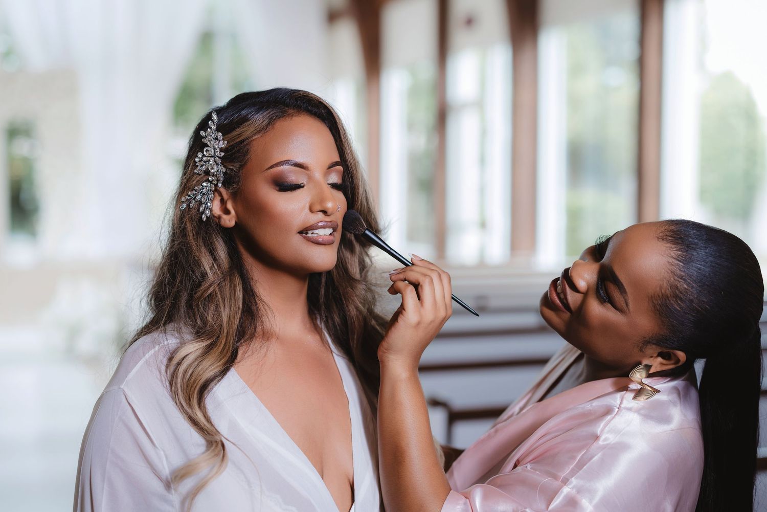 A makeup artist applies finishing touches during wedding preparation.