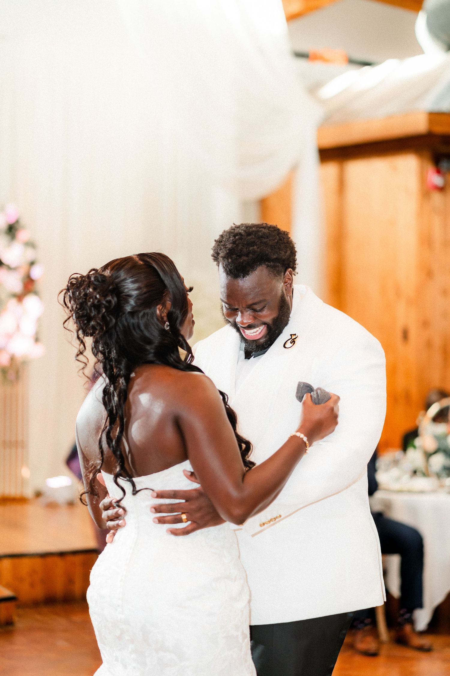 Couple shares their first dance together at a wedding reception in a rustic wooden venue.