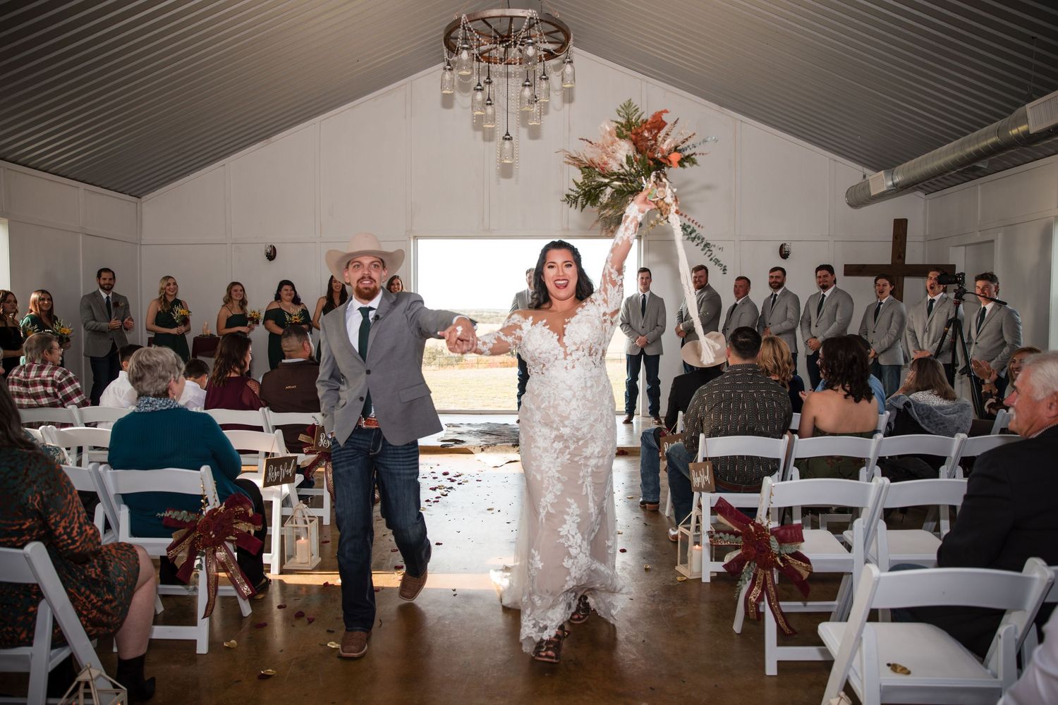 Wide view of a wedding reception venue decorated with white chairs and chandeliers.