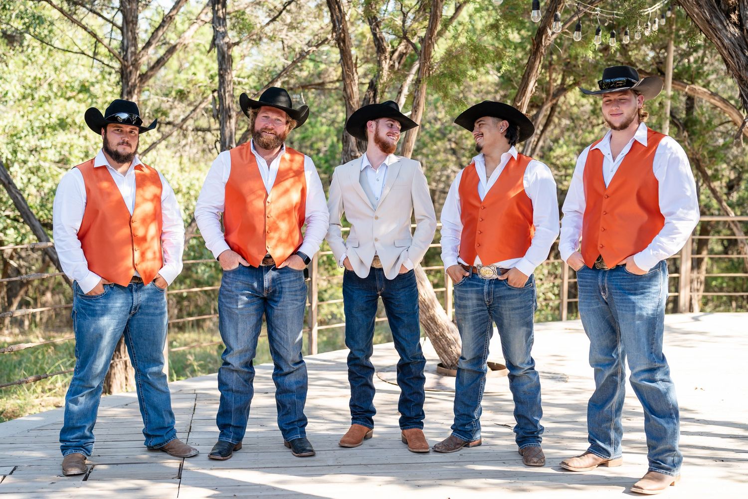 A line of people in matching orange vests and jeans stand on a wooden deck outdoors.