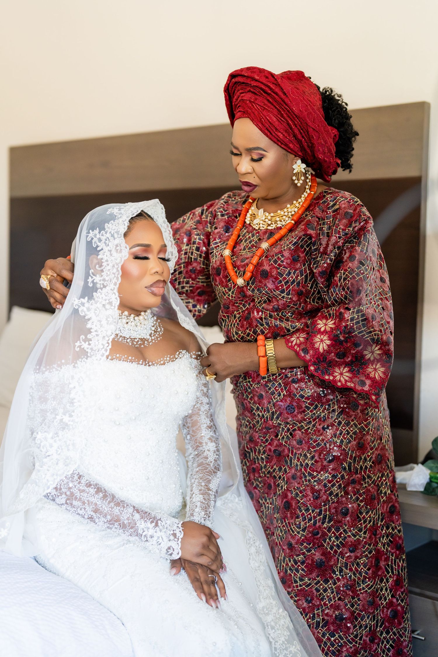 Wedding scene with bride in white lace gown and guest in traditional red and floral attire.