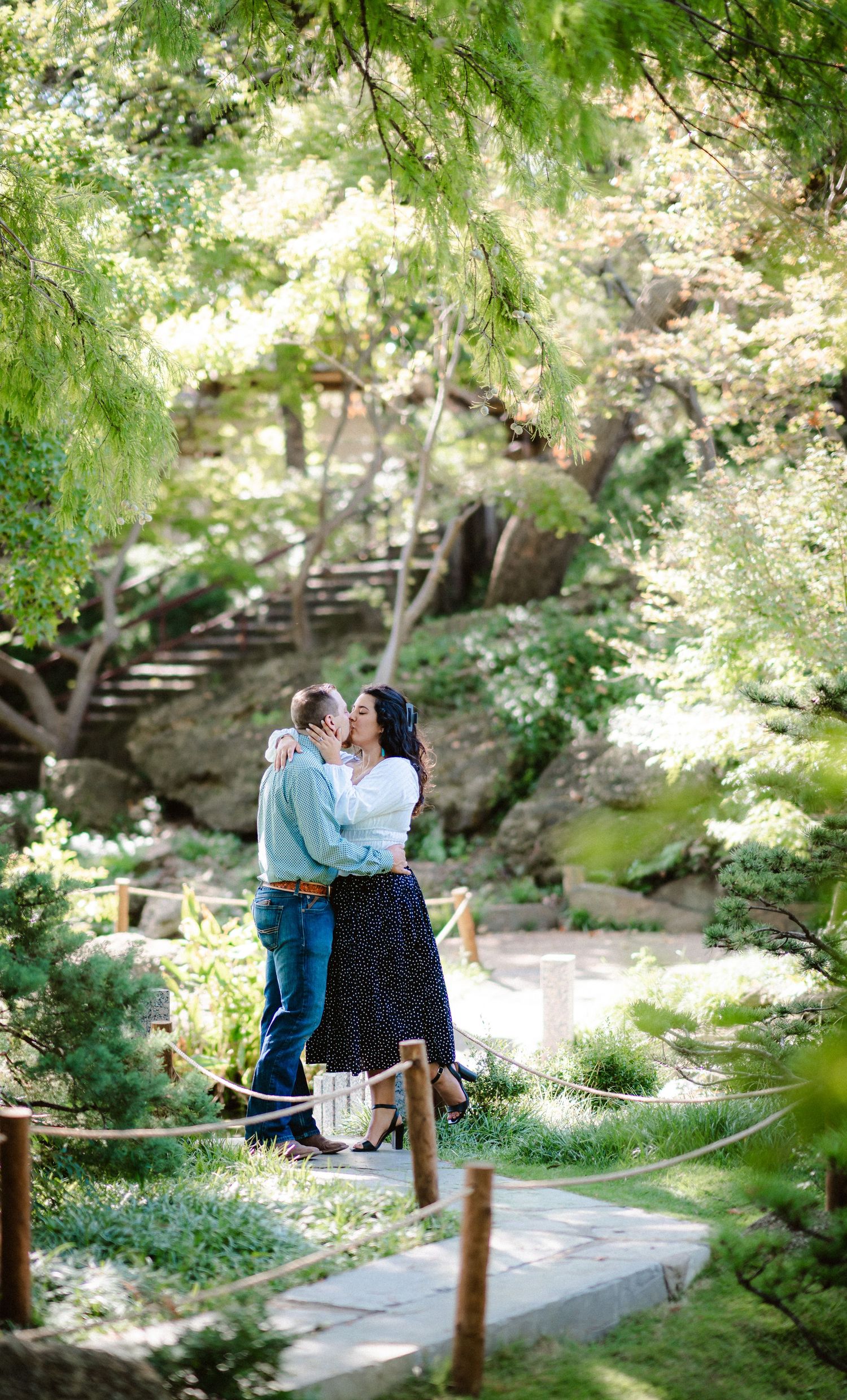 Romantic moment captured on garden path surrounded by green foliage and natural light.