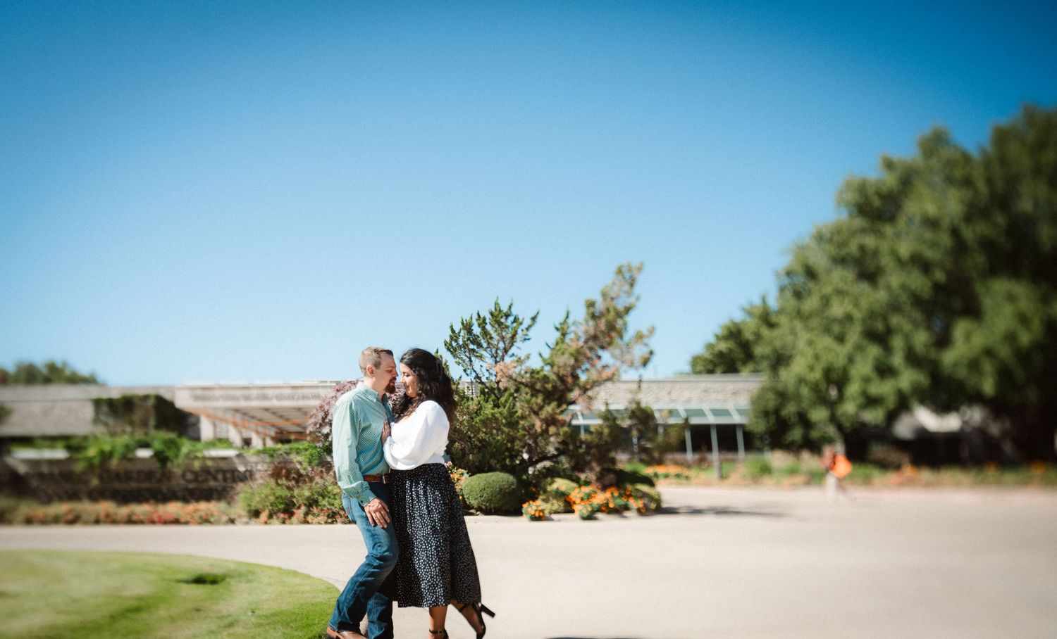 A couple walking together on a path with clear blue skies and green landscape.