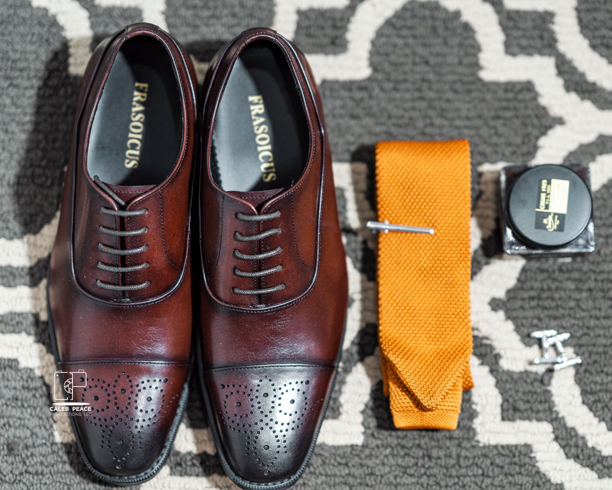 Close-up view of polished brown leather oxford dress shoes arranged on a patterned carpet.