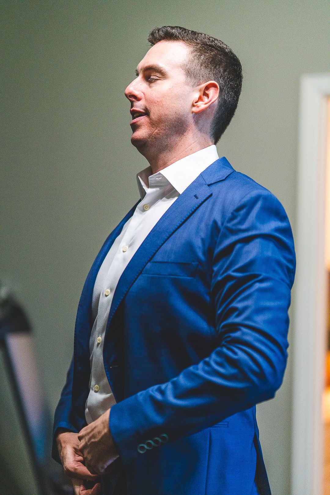 Groom in a bright blue suit and white dress shirt adjusting his attire before the ceremony.