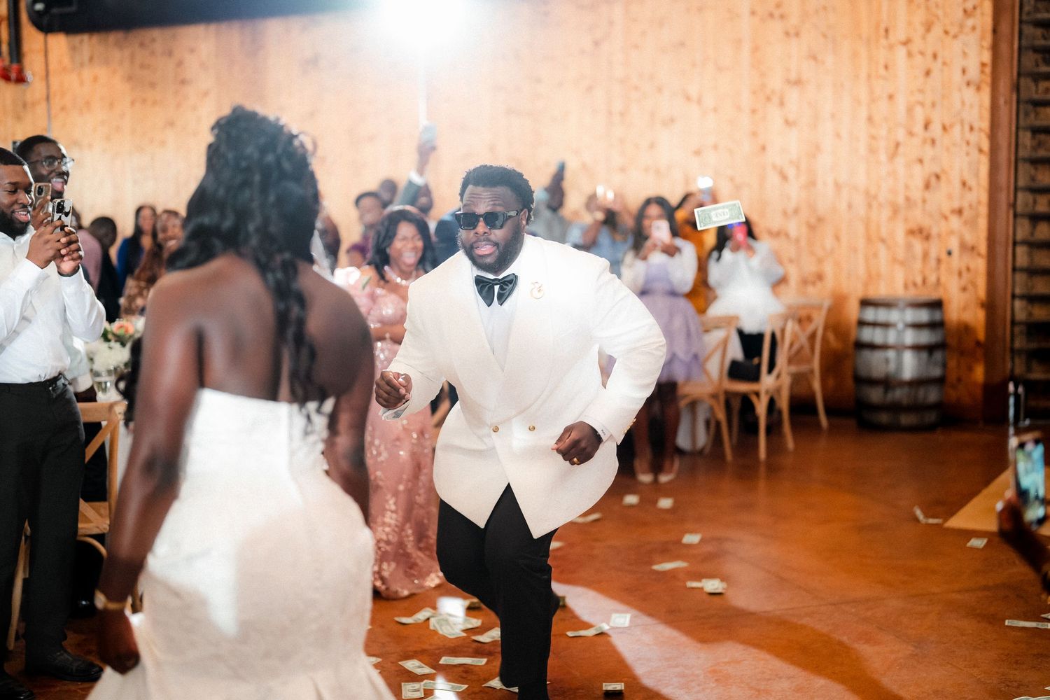 Wedding guests dancing and celebrating at a rustic indoor reception venue.