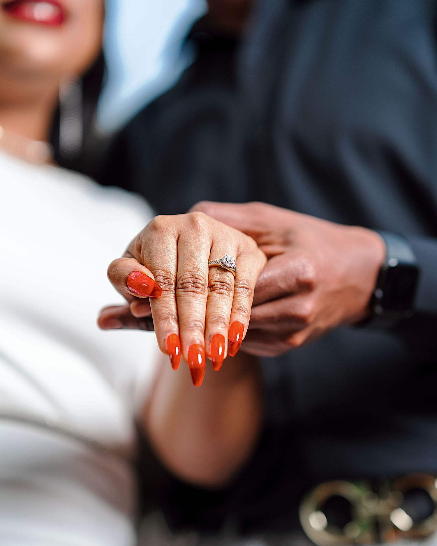 Close-up shots of hands with bright orange nail polish and engagement ring in romantic poses.