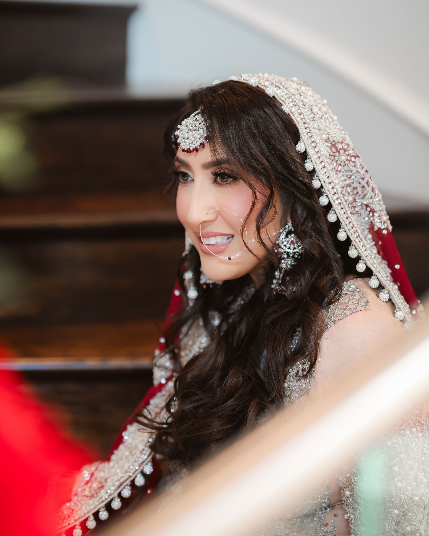 Bride wearing an ornate silver headpiece and traditional wedding attire smiles elegantly.