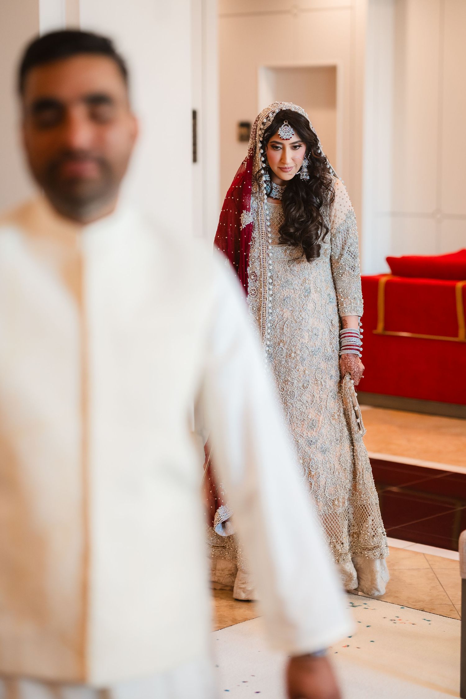 Traditional South Asian wedding attire featuring silver embellished dress and red dupatta.