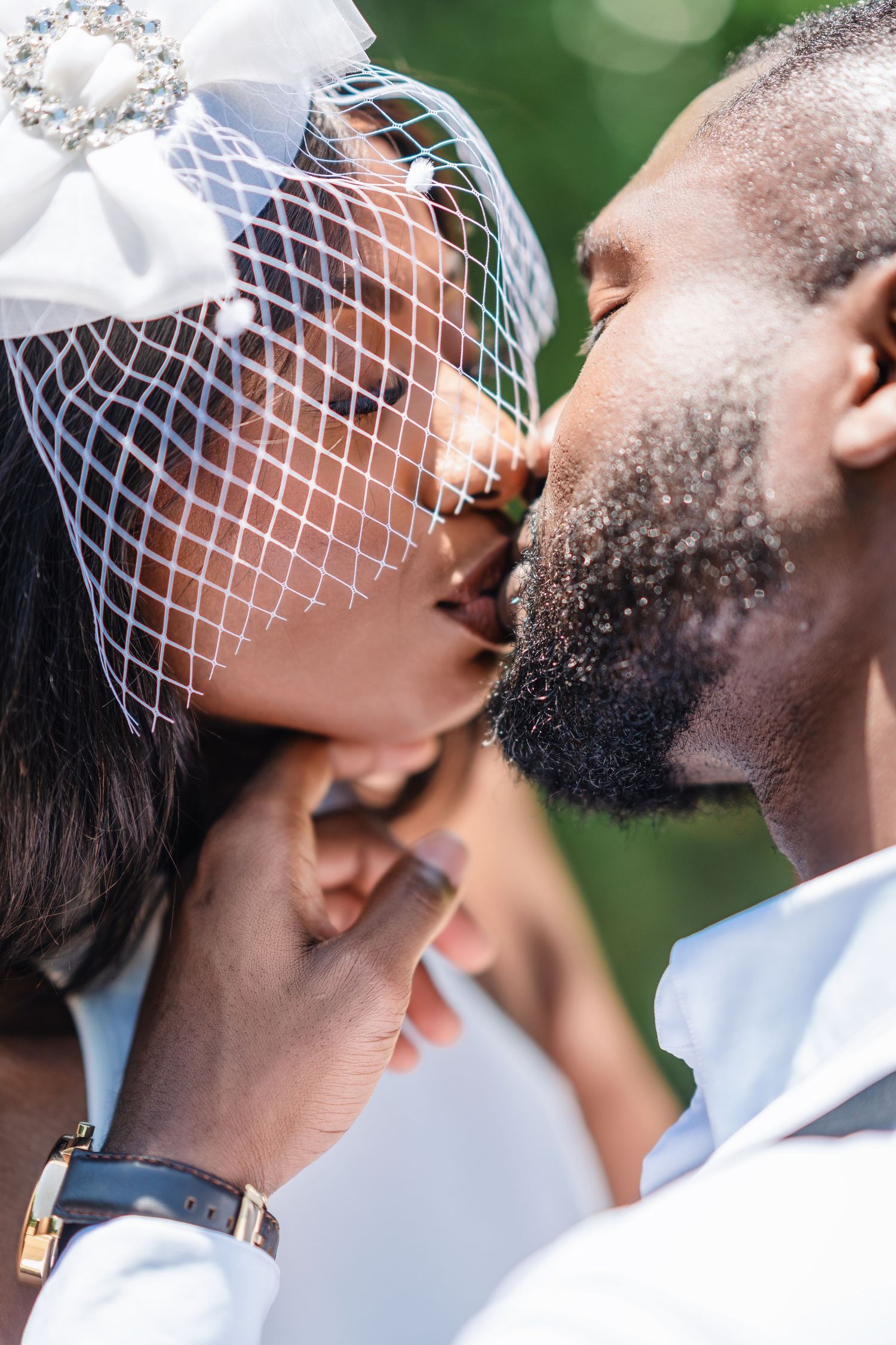 An intimate kiss shared between newlyweds with the bride wearing a decorative white veil.