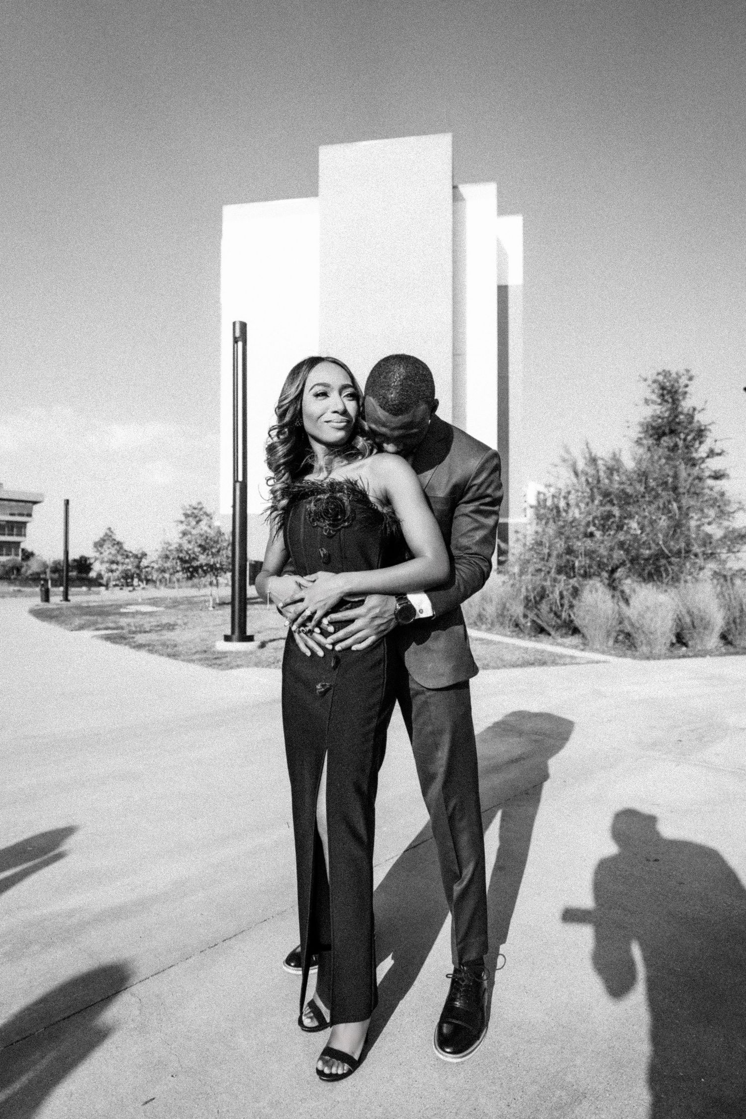 Black and white photo series of a couple embracing on a paved outdoor path.