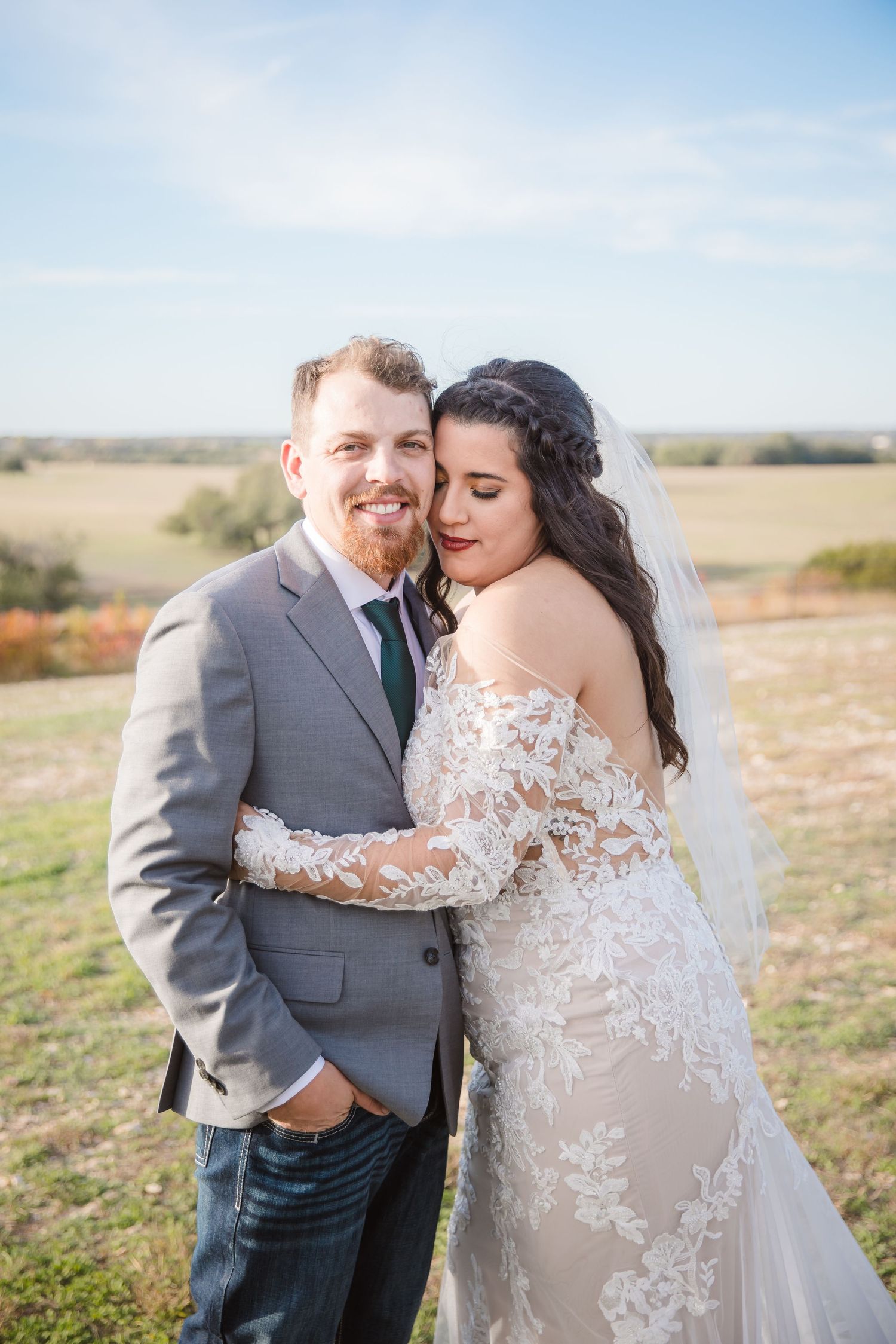 A romantic wedding portrait taken in a rustic outdoor setting with golden sunlight.
