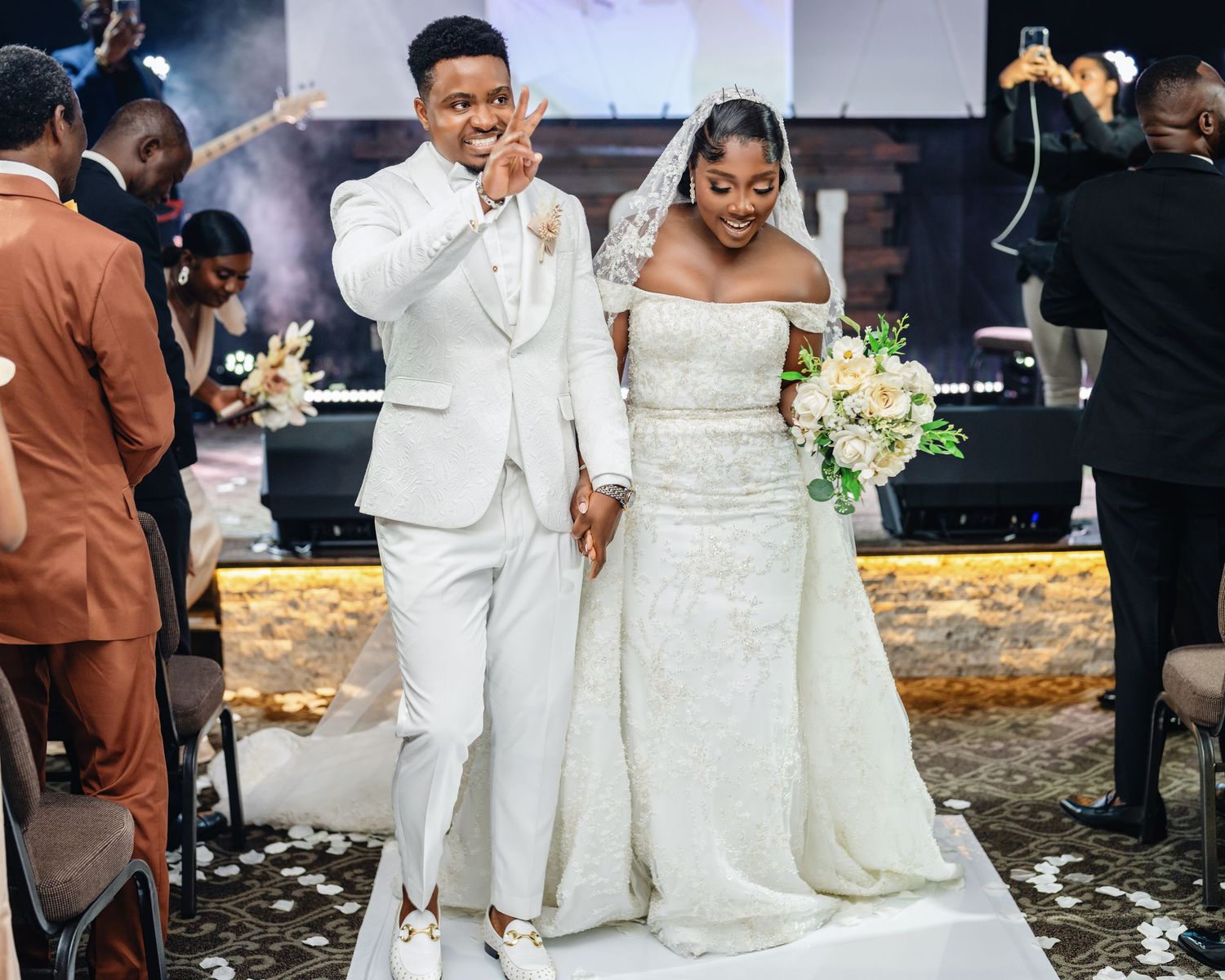 A wedding couple celebrates with guests during an outdoor reception as confetti falls around them in a joyous moment.