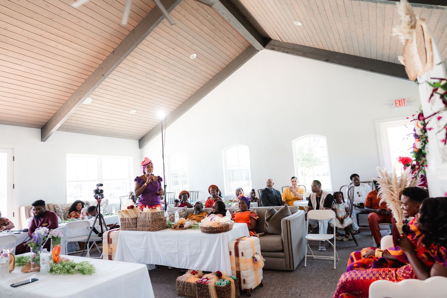 Light-filled reception hall with wooden ceiling beams and white decor.