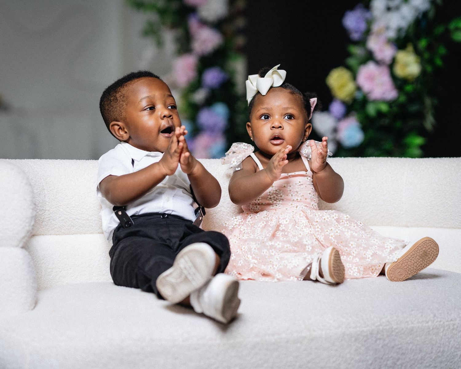 A series of four photos showing a baby in black and white outfits lying on a white blanket, expressing different playful emotions.