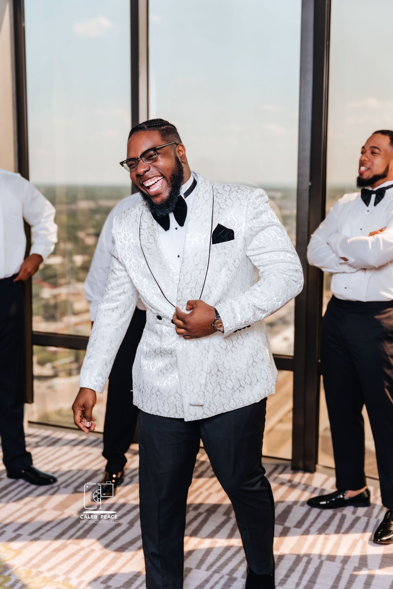 Wedding party members in black and white formal attire pose playfully in a high-rise venue.