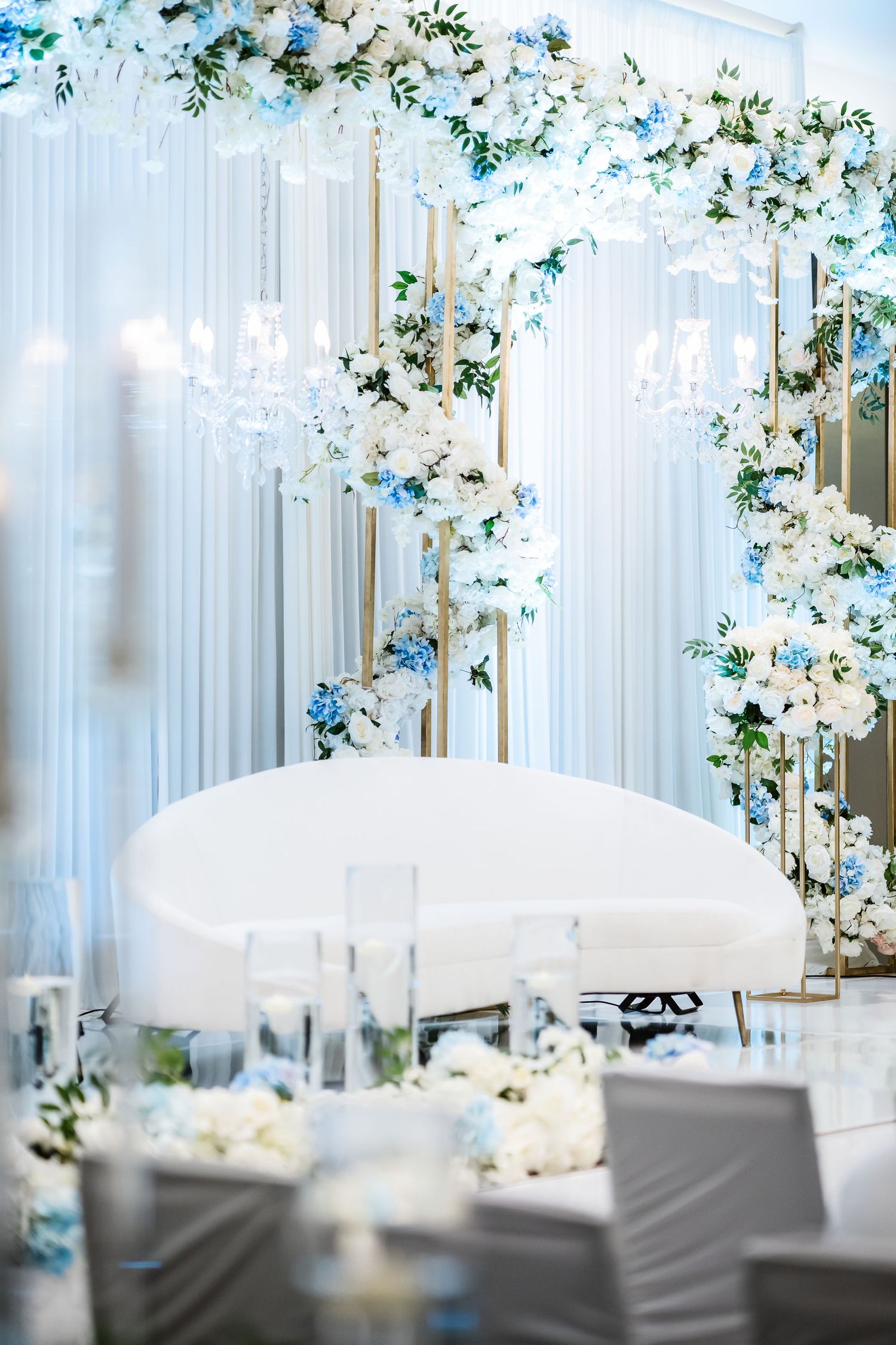 Elegant wedding reception venue decorated with white floral arrangements and sheer curtains creating a romantic atmosphere.
