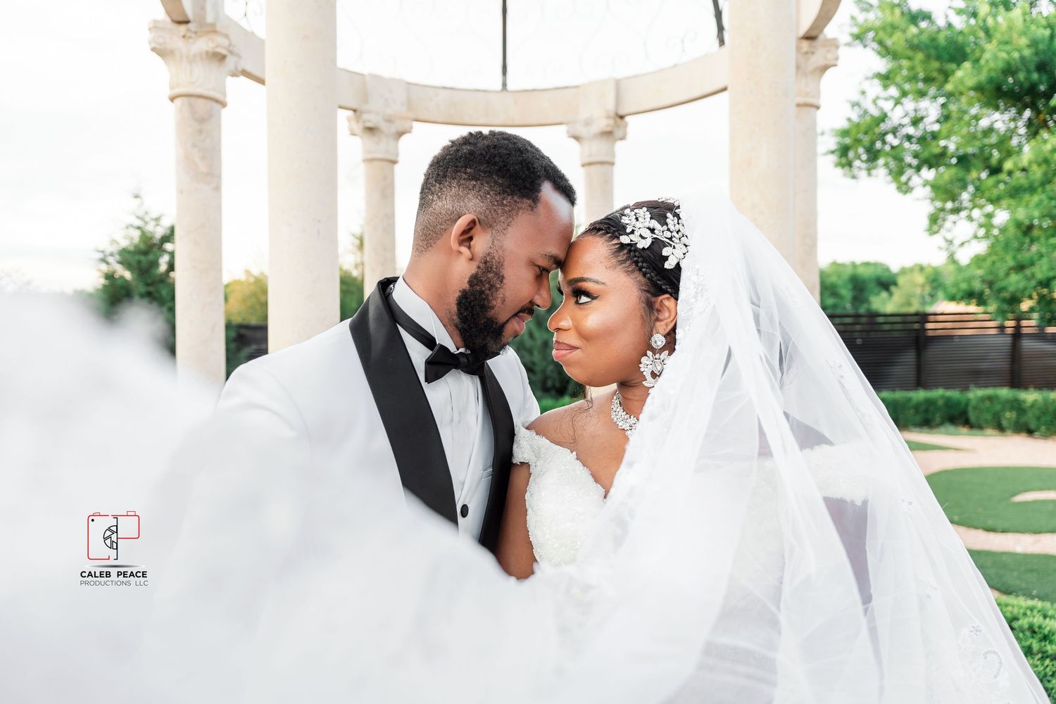 Romantic newlyweds share intimate moments under elegant white columns during an outdoor wedding photoshoot.