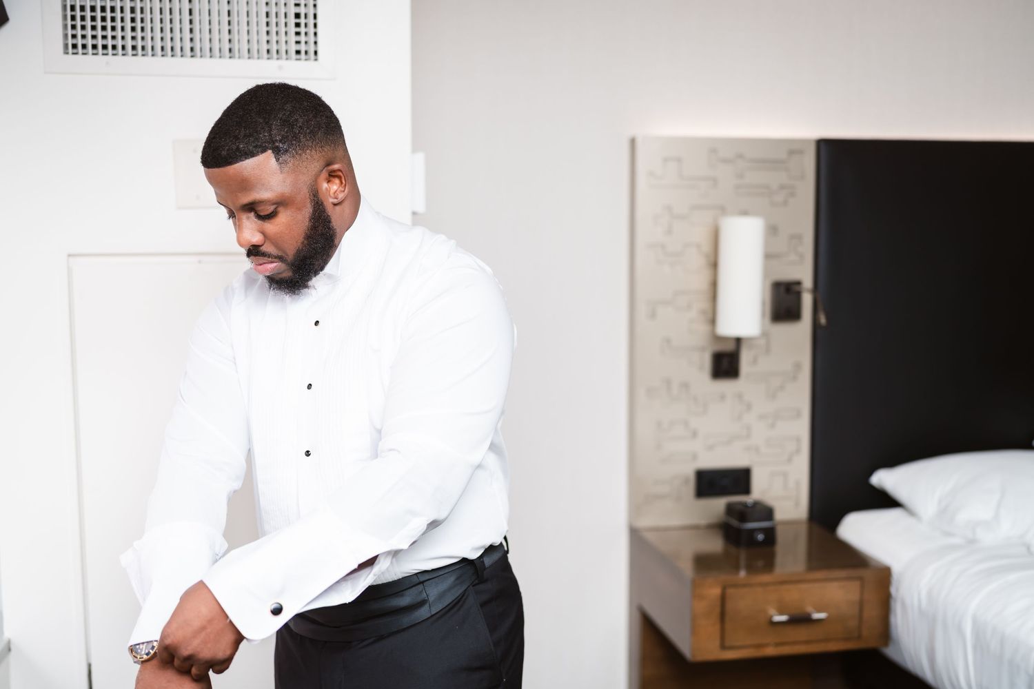 Getting ready moments captured in minimalist modern room with white walls.